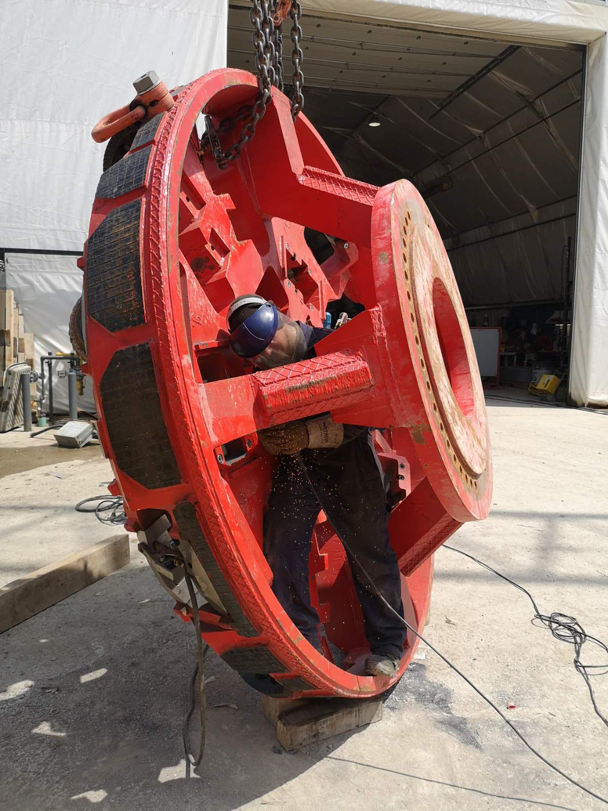 Welder working inside a massive red steel industrial component, performing precision welding and fabrication in Cambridge
